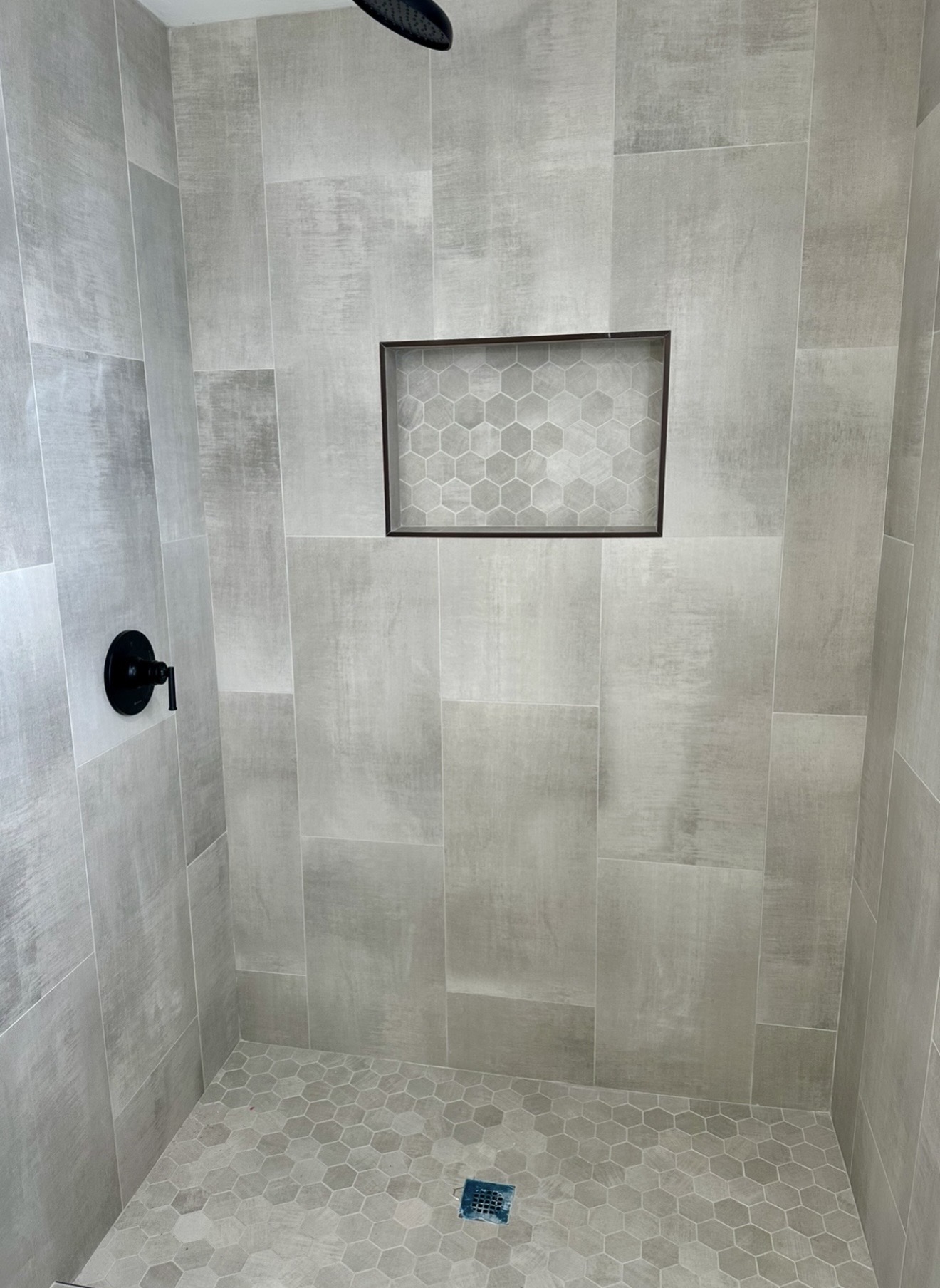 Gray tiled shower with hexagonal feature niche