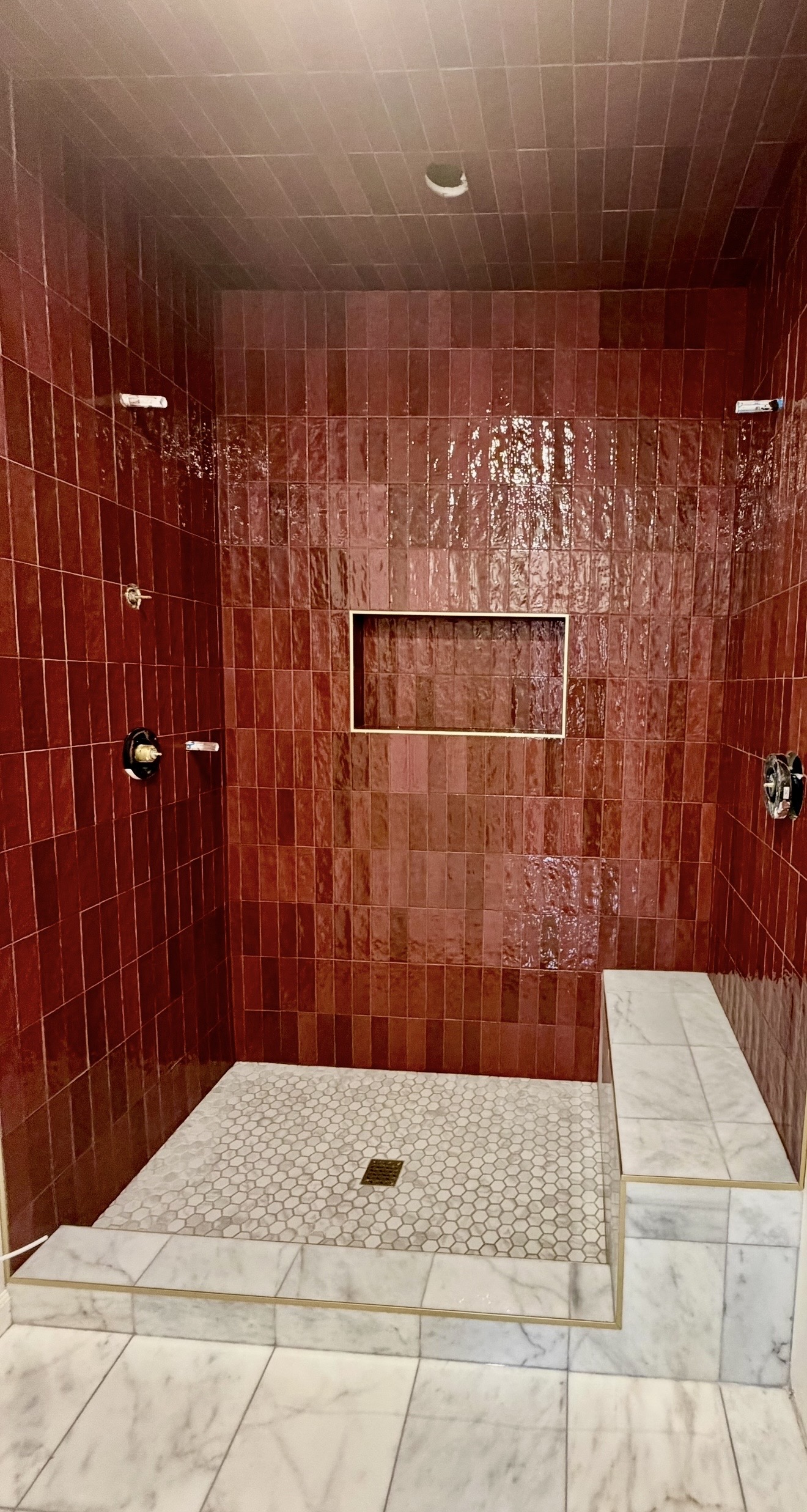 Red tile shower with marble bench and niche