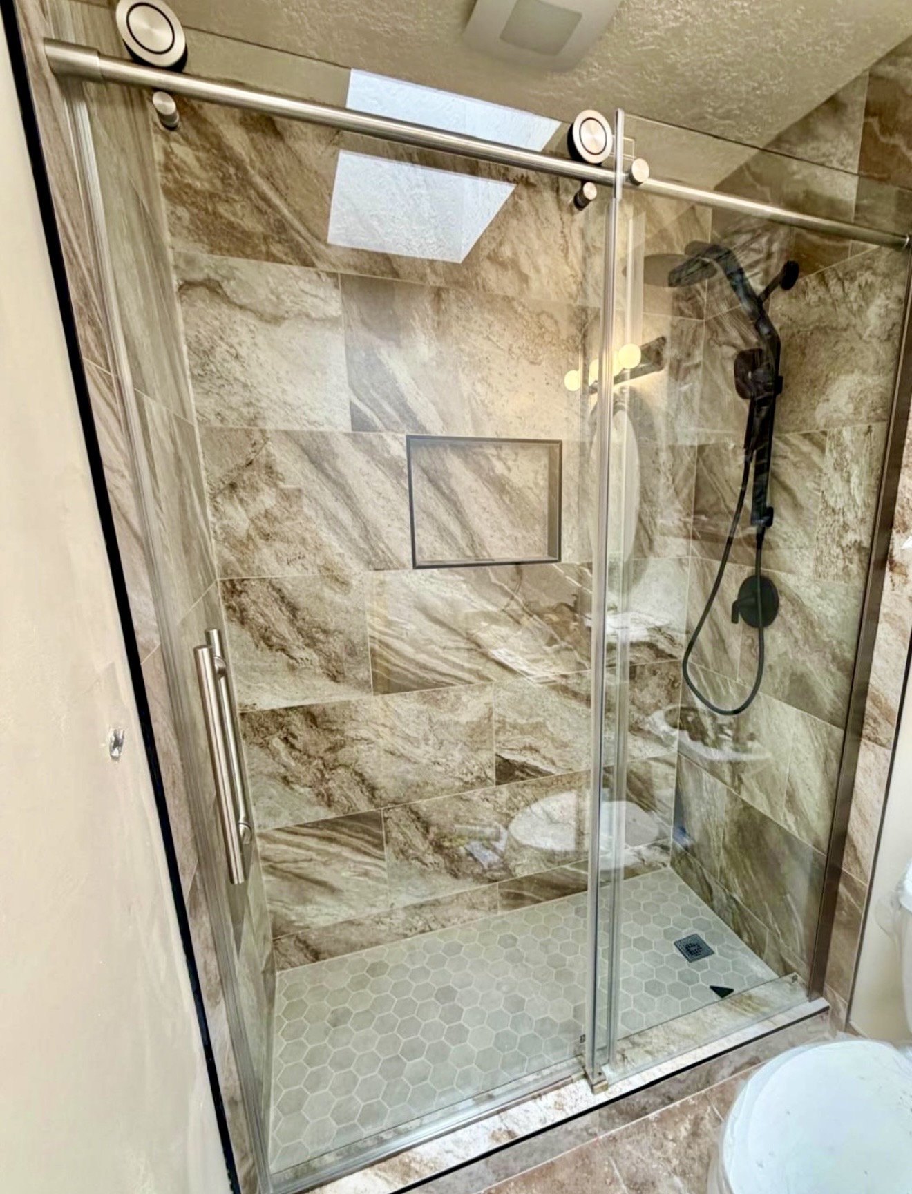 Warm stone tile shower with glass enclosure